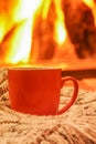 Orange mug for tea or coffee; wool things near cozy fireplace; w