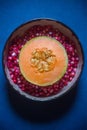 Orange Musk Melon sliced in half surrounded by Pomegranate Seeds. Top View of a Cantaloupe or Honeydew on a Blue Background