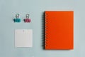 Orange note book with white paper with pastel green and pink clip for business blue background in Instagram style Royalty Free Stock Photo