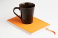 Orange note book white pen and cup Royalty Free Stock Photo