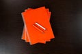 Orange notebooks lying on a dark brown wooden table with an orange and white pens Royalty Free Stock Photo