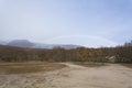 Orange oak trees, snowy mountain, rainbow and cabin.