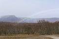 Orange oak trees, snowy mountain and rainbow.