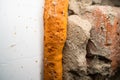 Orange old polyurethane foam between wall and plastic window close-up