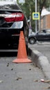 Orange old traffic cone on the road near a care Royalty Free Stock Photo