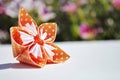Orange origami flower on floral background. Copy space.
