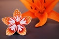 Orange origami flower made of polka dotted paper and lily.