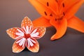 Orange origami flower made of polka dotted paper and real lily.