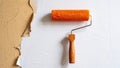 Orange paint roller on a textured wall, preparing for renovation or home improvement project Royalty Free Stock Photo
