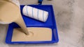 Orange paint with tray and roller. Paint the floor using a roller. Pour the paint from the bucket into the tray. A man Royalty Free Stock Photo