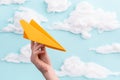 Orange paper airplane in child`s hand flying on blue sky background Royalty Free Stock Photo