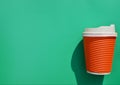 Orange paper cup with coffee or drink on designer green or turquoise background