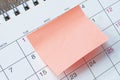 Orange paper sticky note and stuck to a calendar background. Reminder concept. Royalty Free Stock Photo