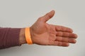 orange paper wristband mockup on persons arm. Clear adhesive bangle wristlet sticker with entry number on hand of middle-aged Royalty Free Stock Photo