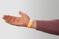 orange paper wristband mockup on persons arm. Clear adhesive bangle wristlet sticker with entry number on hand of middle-aged Royalty Free Stock Photo