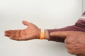 orange paper wristband mockup on persons arm. Clear adhesive bangle wristlet sticker with entry number on male hand of middle-aged Royalty Free Stock Photo