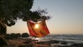 An orange pareo hanging from a tree at a beach