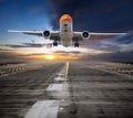 Orange passenger plane takes off from the airport runway during the sunset