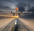 Orange passenger plane takes off from the airport runway during the sunset. Front view