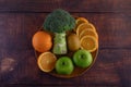 Orange pieces, apple, kiwi, and Broccoli on a wooden plate