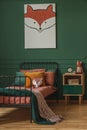 Orange pillow on single bed in dark green teenager bedroom