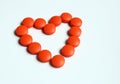 Orange pills that are composed to shape of heart isolated on white background. Love to medicine