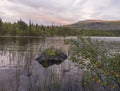 Orange pink sunset over lake Sjabatjakjaure in Parte in Sweden Lapland. Mountains, birch trees, spruce forest, rock boulders and Royalty Free Stock Photo