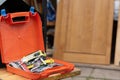 Orange plastic box with toolkit on bench against wooden door