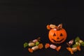 Orange plastic candy basket in the shape of a pumpkin jackolantern on a black background