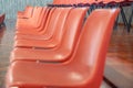 Orange plastic chairs lined up, seen in profile Royalty Free Stock Photo