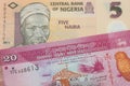 A orange, plastic five naira note from Nigeria paired with a pink and white twenty rupee bank note from Sri Lanka.