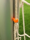 Orange plastic hanger in aluminum pole in soccer gate, soccer football net. Light green grass on football playground