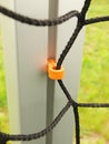 Orange plastic hanger in aluminum pole in soccer gate, soccer football net. Light green grass on football playground