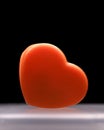 Orange plastic heart against black background, Valentines day concept