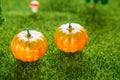 Orange plastic pumpkins on a green meadow with green grass. Macro shooting. Fairy tale.