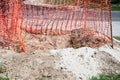 Orange plastic safety net or barrier on the street to protect excavating construction site close up Royalty Free Stock Photo