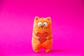 Orange plush cat with red heart so cute on the pink background