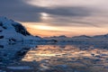 Orange polar sunset over the mountains with glaciers and drifting melted icebergs at Lemaire Strait, Antarctica