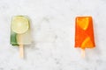 Orange popsicle and lime popsicle on marble table Royalty Free Stock Photo