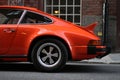 Orange Porsche 911 outside restaurant in an alley