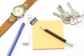 Orange post it with keys watch and bulldog clip and black pencil