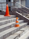 Orange protective cones on broken steps in office building warn of danger.