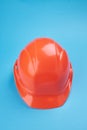 orange protective helmet and safety glasses near it on a bright blue background. protective workwear and construction Royalty Free Stock Photo