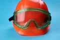 Orange protective helmet and safety glasses near it on a bright blue background. protective workwear and construction Royalty Free Stock Photo