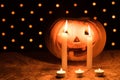 Orange pumpkin as a head with carved eyes and a smile with candles on a black background with a garland to the Halloween party Royalty Free Stock Photo