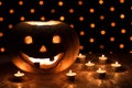 Orange pumpkin as a head with carved eyes and a smile with candles on a black background with a garland to the Halloween party Royalty Free Stock Photo