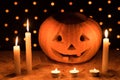 Orange pumpkin as a head with carved eyes and a smile with candles on a black background with a garland to the Halloween party Royalty Free Stock Photo