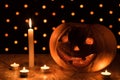 Orange pumpkin as a head with carved eyes and a smile with candles on a black background with a garland to the Halloween party Royalty Free Stock Photo