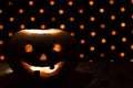 Orange pumpkin as a head with carved eyes and a smile with candles on a black background with a garland to the Halloween party Royalty Free Stock Photo