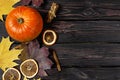 Orange pumpkin, cinnamon, slices of dried orange, autumn colorful leaves and checkered plaid on a dark wooden background top view